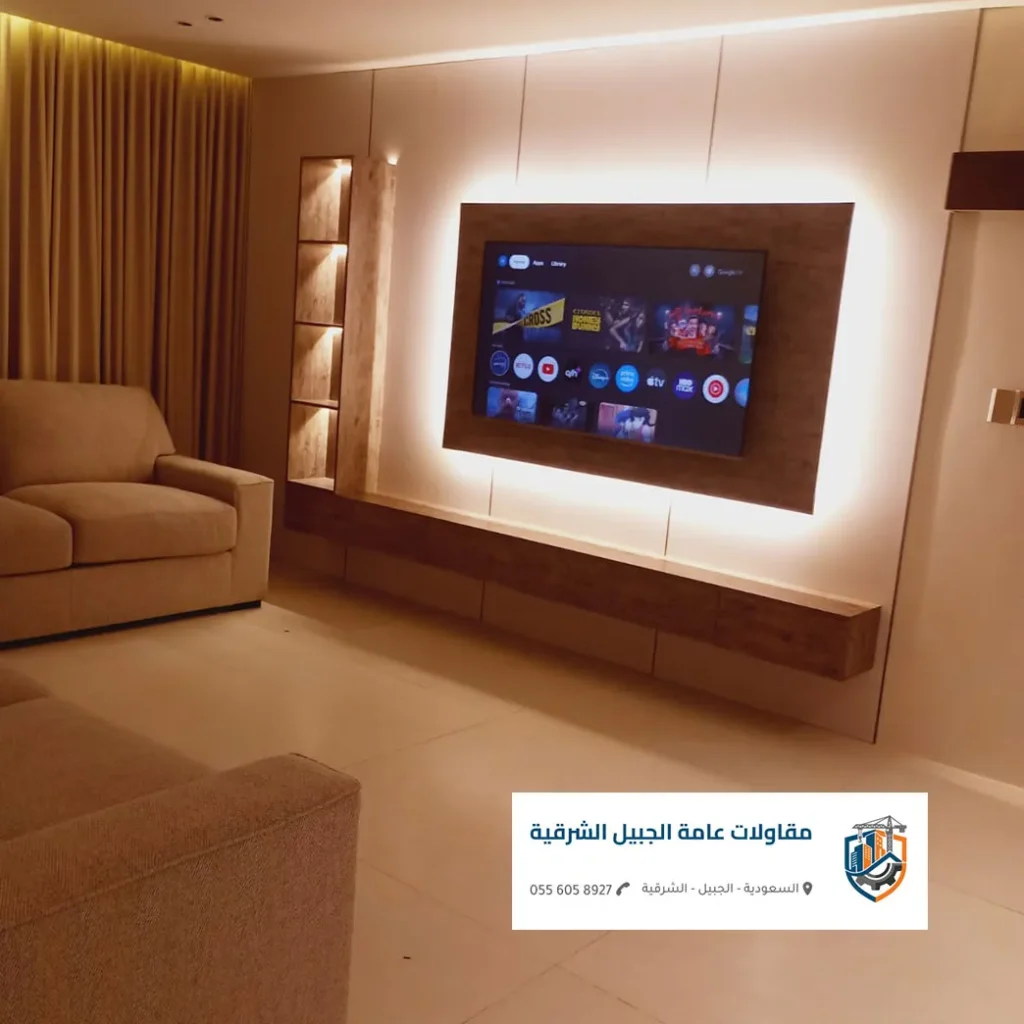 ديكور شاشة يجمع بين بديل الرخام الأبيض وبديل الخشب البني مع أرفف مخفية في الجبيل.